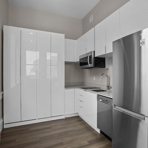 This image shows a modern kitchen with stainless steel appliances, white cabinets, a microwave, and a dishwasher, all set in a compact space.